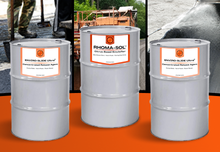 Three gray industrial drums with orange-and-white labels on an orange floor; labels read 'Enviro-Slide Ultra' and 'Rhoma-Sol' in an industrial setting.